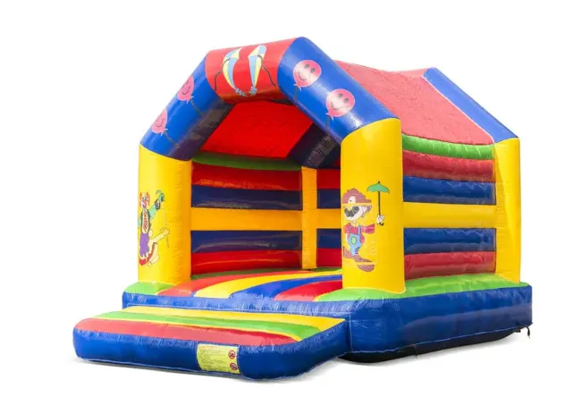 Standaard Circus Springkussen in felle rood, blauw, gele en groene kleuren, met overdekte springruimte, netwanden en een lage glijbaan.